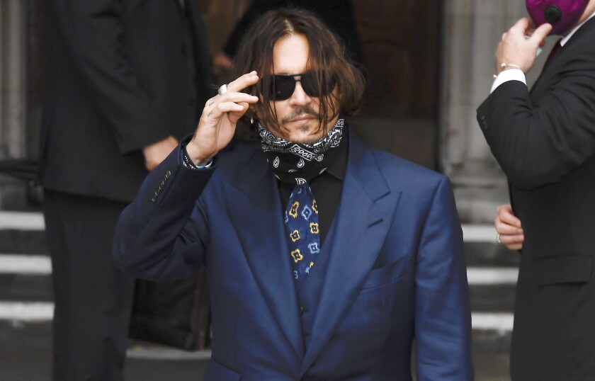 Depp vs Heard: The Aftermath And What it Meant for the World 89 A man in a sportscoat and a scarf brushes hair from his face